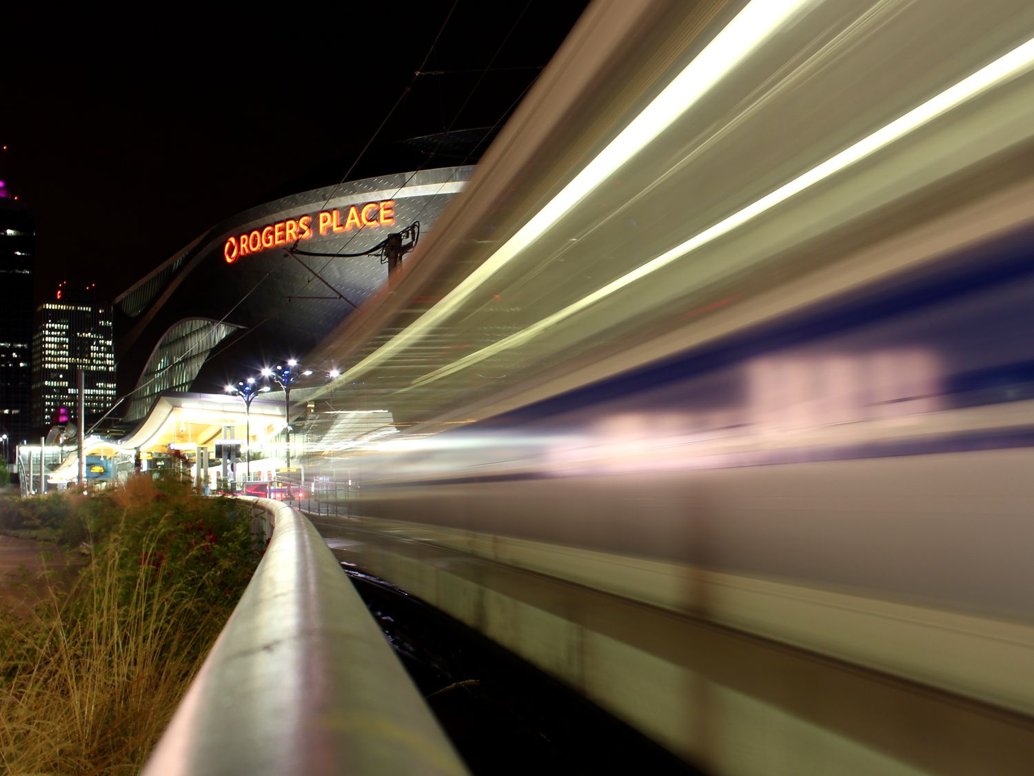Long-exposure light trails past Rogers Place in downtown Edmonton at night — photography services Edmonton