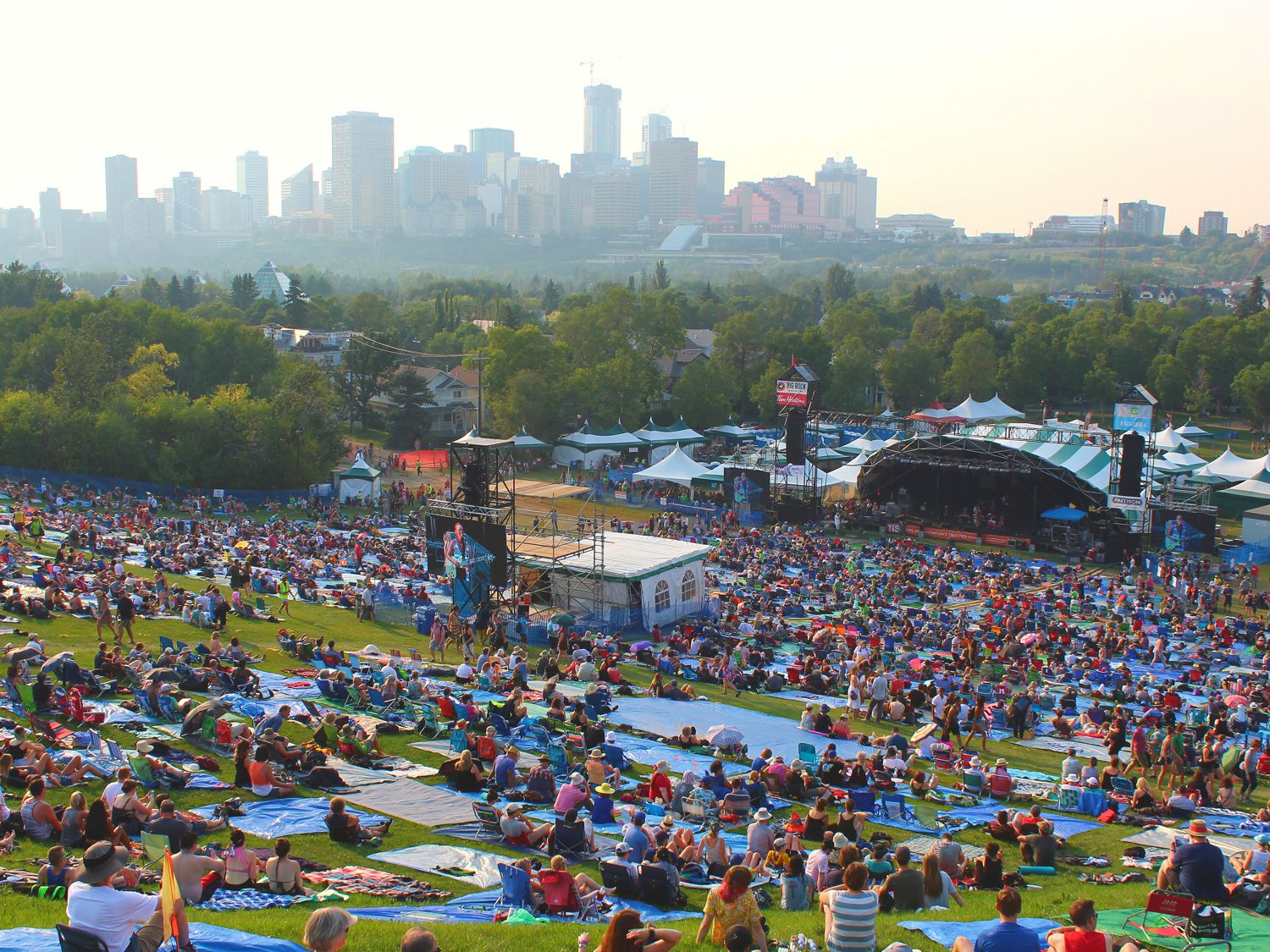 A large crowd gathered on the hill at an Edmonton folk festival with the downtown skyline behind — social media strategy Edmonton